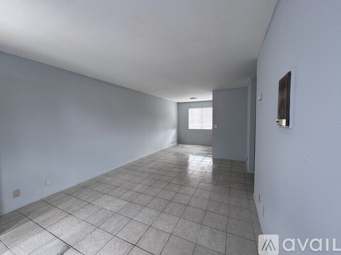 A spacious room with white walls and a tiled floor.