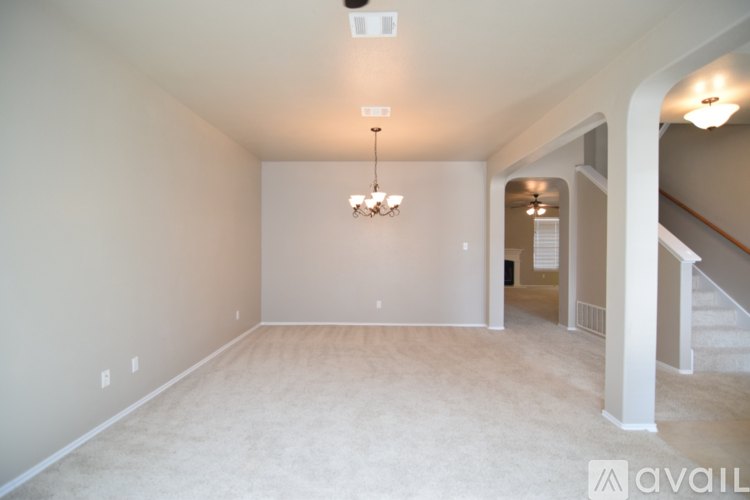 A spacious room with a chandelier and a staircase.