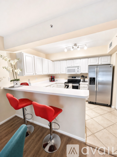 A kitchen with a white counter and red bar stools.