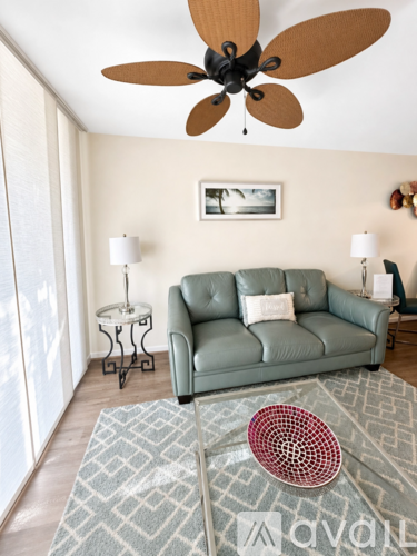 A living room with a green couch and a ceiling fan.