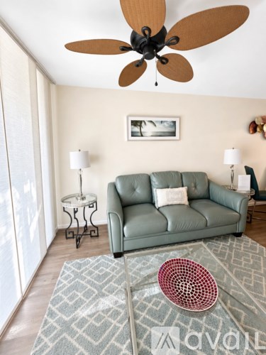 A living room with a green couch and a ceiling fan.