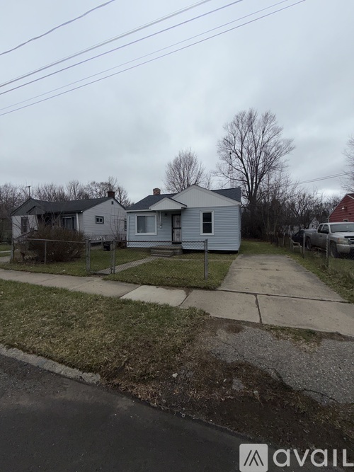 A house with a grey roof and a white fence is in the image.
