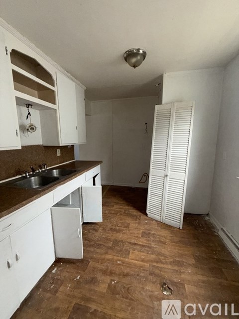 A kitchen with white cabinets and a wooden floor.