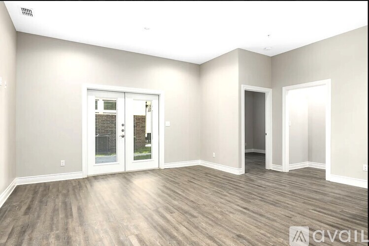 A spacious room with wood flooring and a door leading to a balcony.