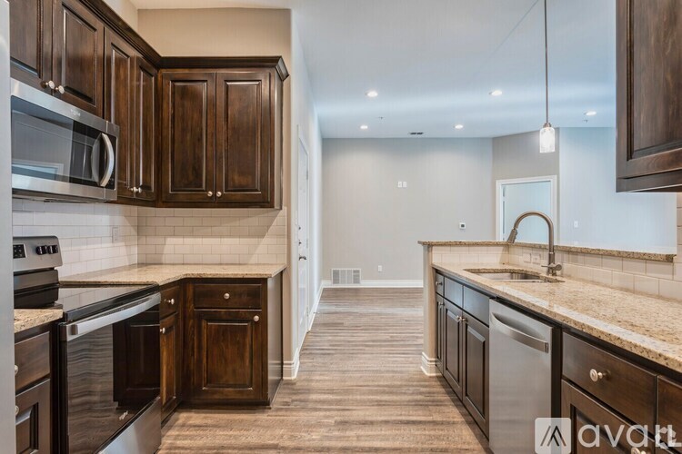A kitchen with dark wood cabinets and a granite countertop.