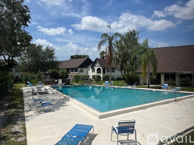 A pool with blue chairs and a house in the background.