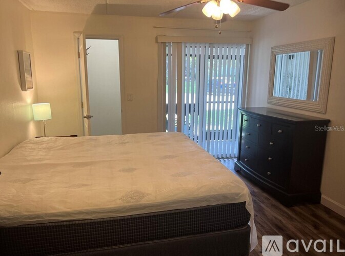 A bedroom with a large bed, a dresser, and a window with blinds.