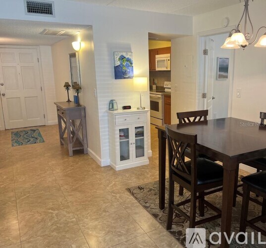 A kitchen with a table and chairs in the foreground and a painting on the wall.