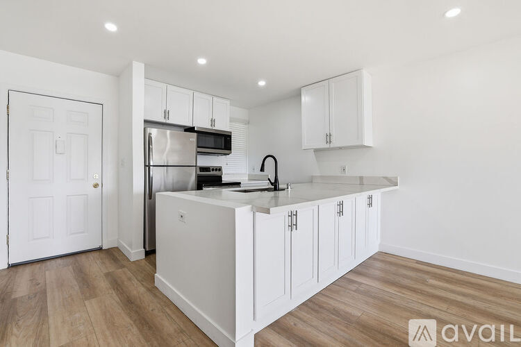 A kitchen with white cabinets and a stainless steel refrigerator.