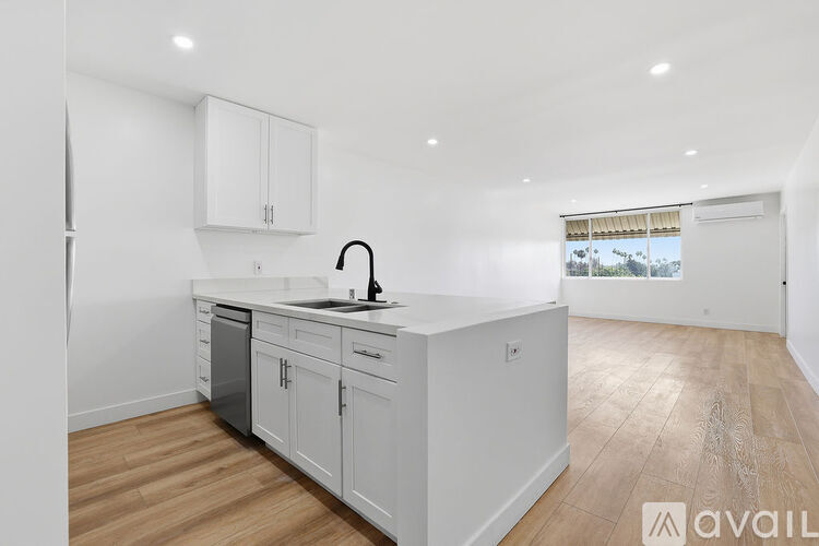 A kitchen with white cabinets and a wooden floor.