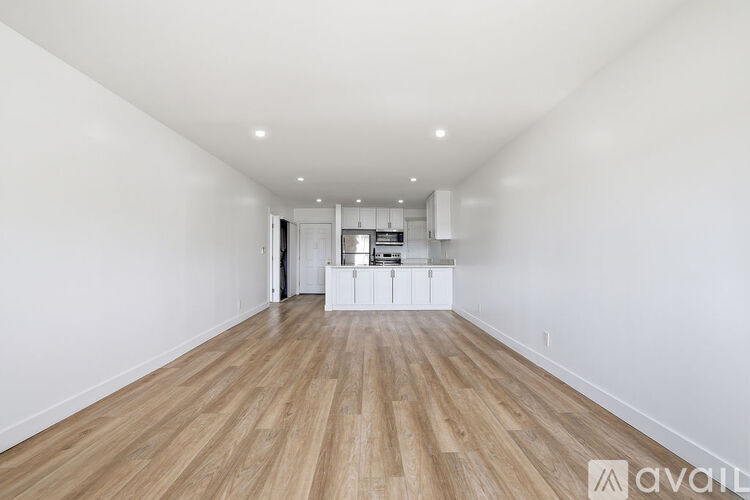 A spacious room with wooden flooring and white walls.