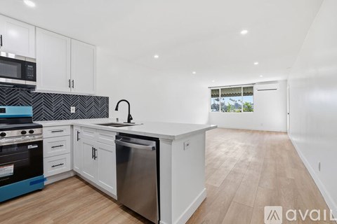 A kitchen with white cabinets and a wooden floor.