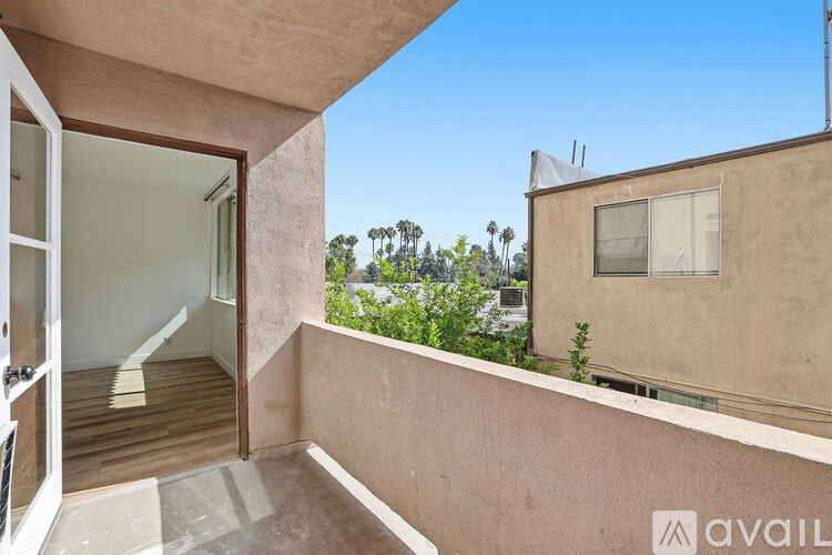 A balcony with a glass door leading to a room with a view of trees.