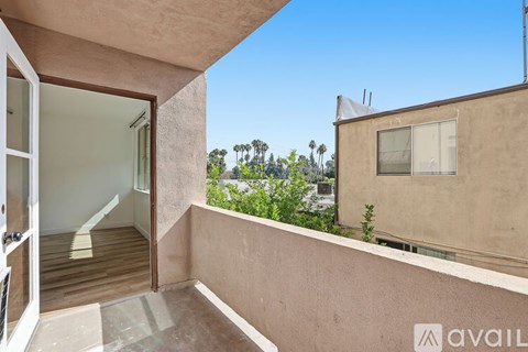 A balcony with a glass door leading to a room with a view of trees.