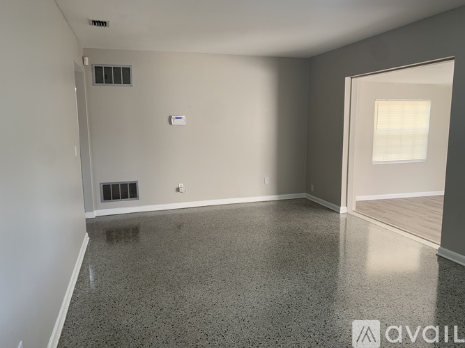 A spacious room with a grey floor and white walls.
