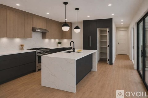 A modern kitchen with a white marble island and dark wood cabinets.