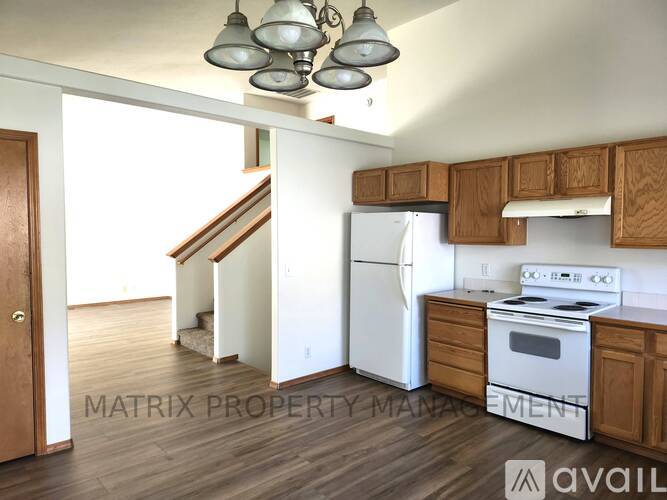 A kitchen with wooden cabinets and white appliances is available for rent.