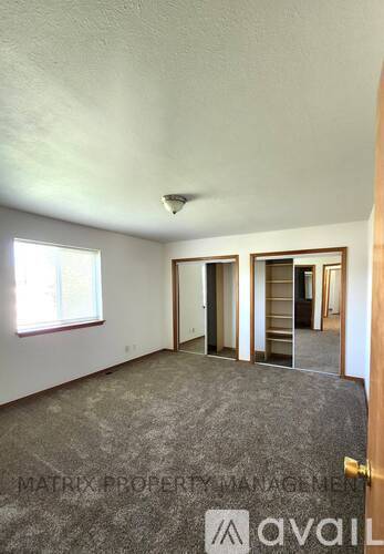 A room with a carpeted floor and a door leading to another room.