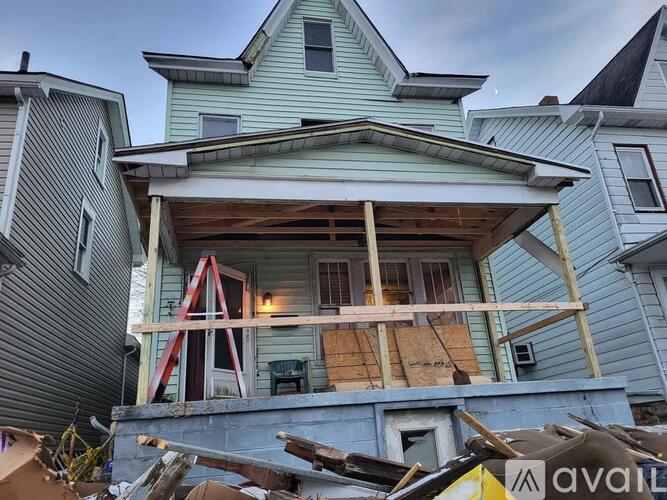 A house with a blue exterior is in the process of being demolished.