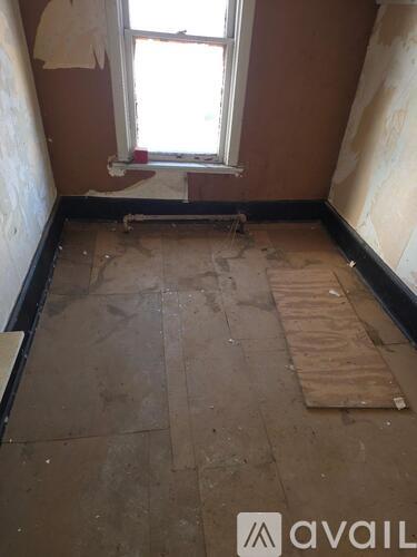 A room with a window and a wooden plank on the floor.