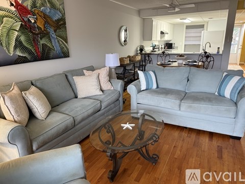 A living room with a grey couch, a coffee table, and a painting of a bird on the wall.