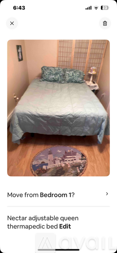 A bedroom with a bed, pillows, and a small table with a lamp.