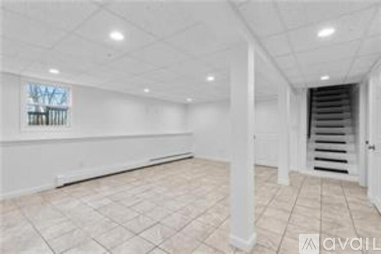A spacious room with a tiled floor and a staircase leading to another level.