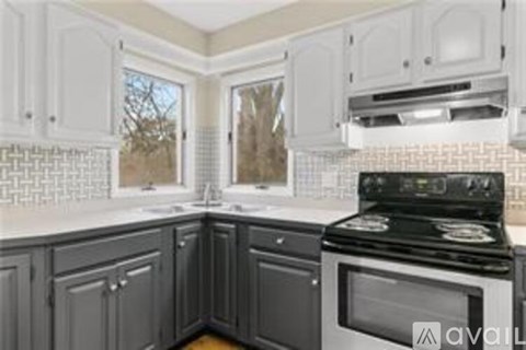 A kitchen with a black stove top oven and white cabinets.