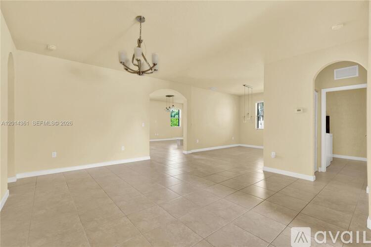 A spacious room with a chandelier and a doorway leading to another room.