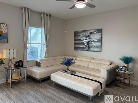 A living room with a white sofa and a glass table with a hat on it.
