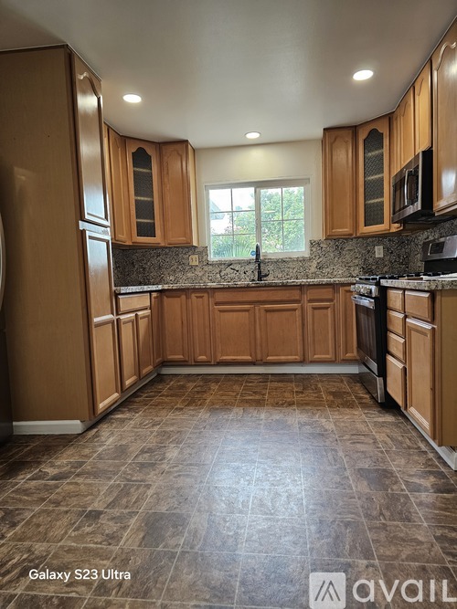 A kitchen with wooden cabinets and a tiled floor.