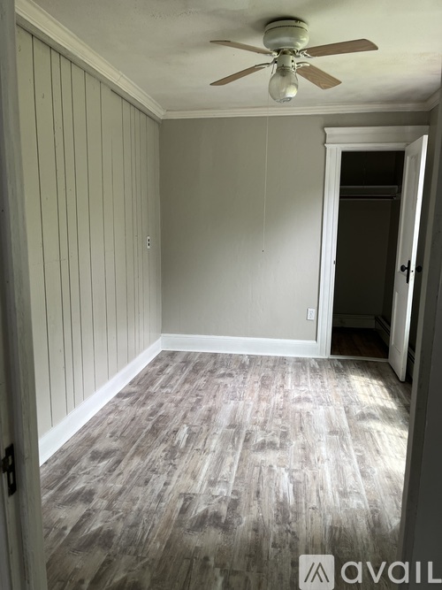 A room with a ceiling fan and wood flooring.