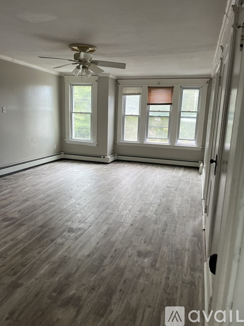 A room with a ceiling fan and wooden flooring.