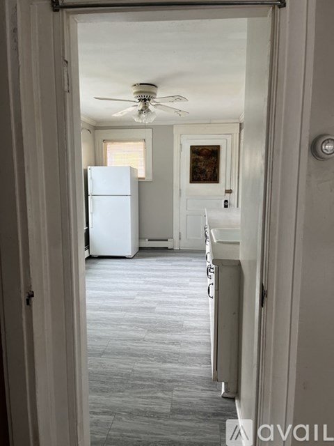 A white refrigerator is in a kitchen with a ceiling fan.