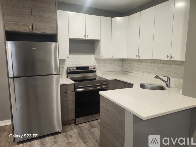 A modern kitchen with a stainless steel refrigerator and white cabinets.