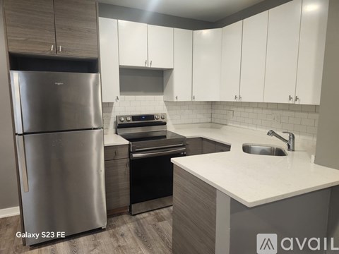 A modern kitchen with a stainless steel refrigerator and white cabinets.