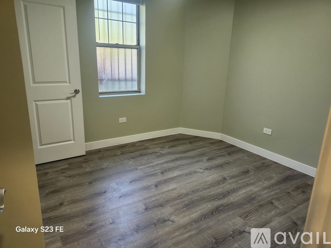 A room with a wooden floor and a window with a white door.