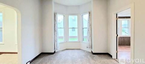 A spacious room with a large window and carpeted floor.