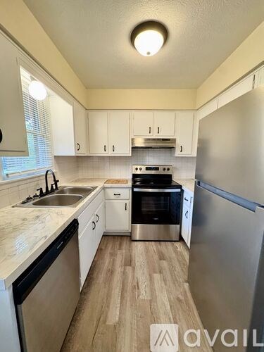 A kitchen with white cabinets and a marble countertop.