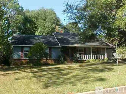 A house with a porch and a tree in front.