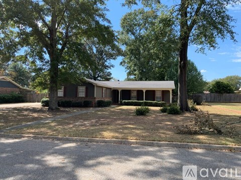 A house with a gravel driveway and trees in front.