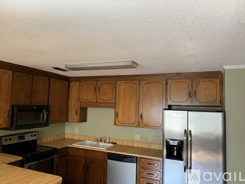 A kitchen with wooden cabinets and a stainless steel refrigerator.