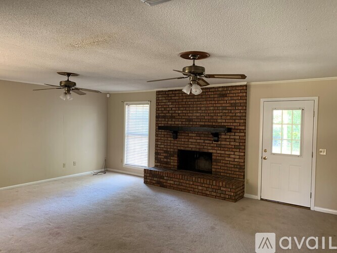 A living room with a brick fireplace and two ceiling fans.