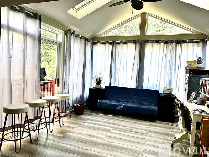 A living room with a blue couch, a wooden table, and a ceiling fan.