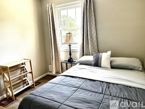 A bedroom with a large bed and a window with curtains.