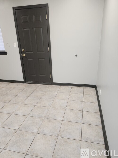 A room with a black door and tiled floor.