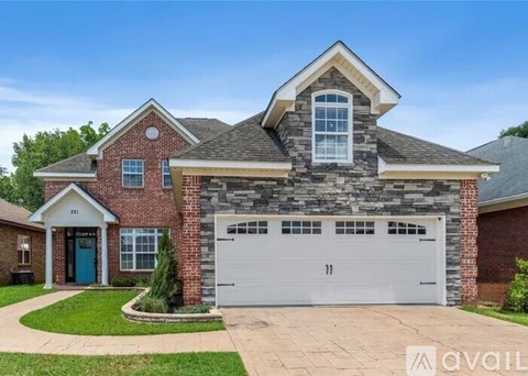 A house with a stone facade and a white garage door is for sale.