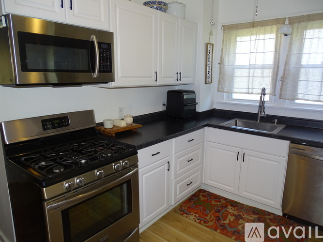 A kitchen with white cabinets and black countertops.