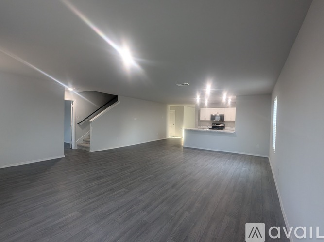 A spacious room with wooden flooring and a staircase leading to another level.
