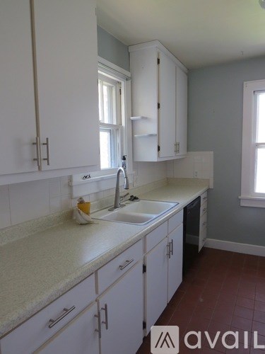 A kitchen with white cabinets and a marble countertop.